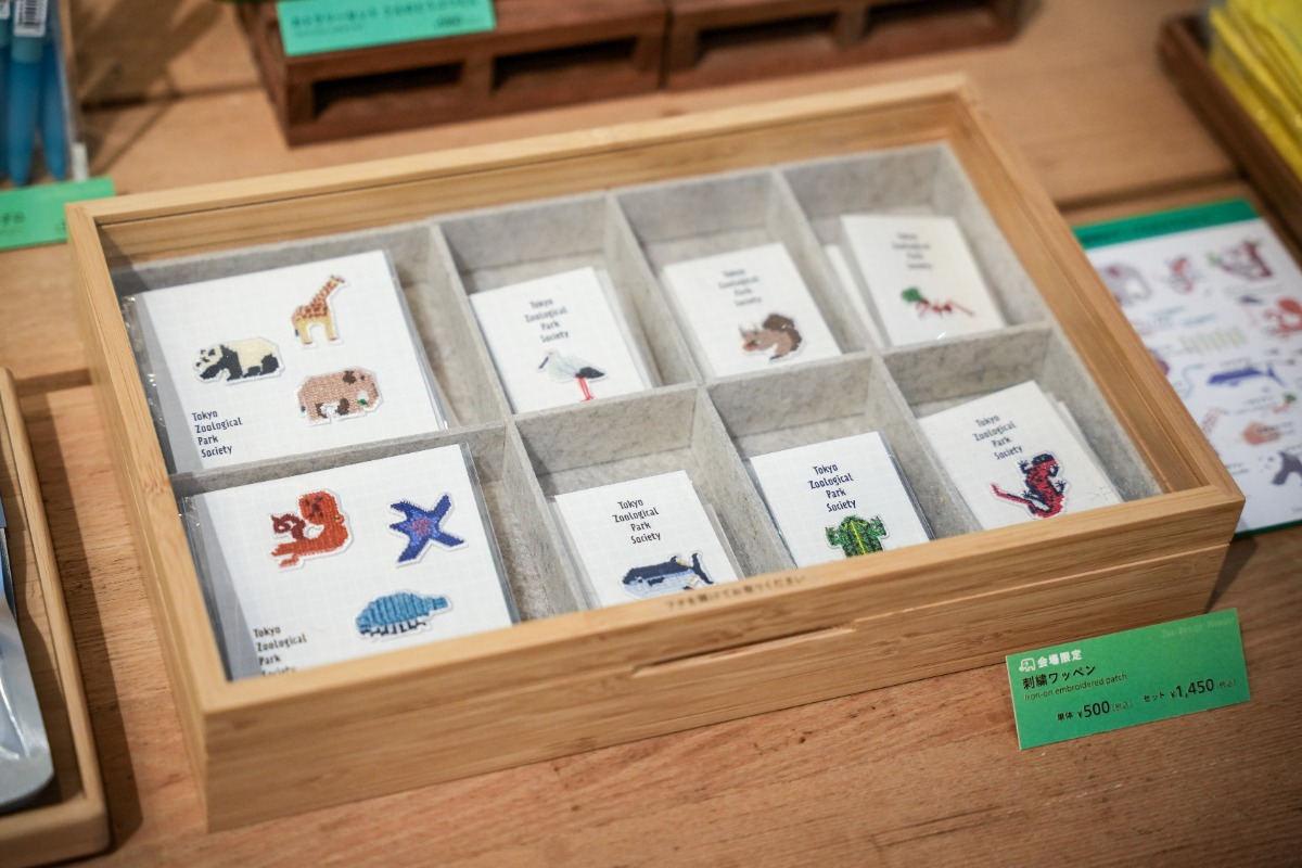 会場限定販売グッズ。刺繍ワッペン1個：500円（アジアゾウ、コウノトリ、二ホンリス、クロマグロ、トウキョウダルマガエル、アカハライモリ、ハキリアリ計6種）、3個セット：1，450円 （①アジアゾウ、ジャイアントパンダ、キリン ②イトマキヒトデ、マダコ、ダイオウグソクムシ計2種）。