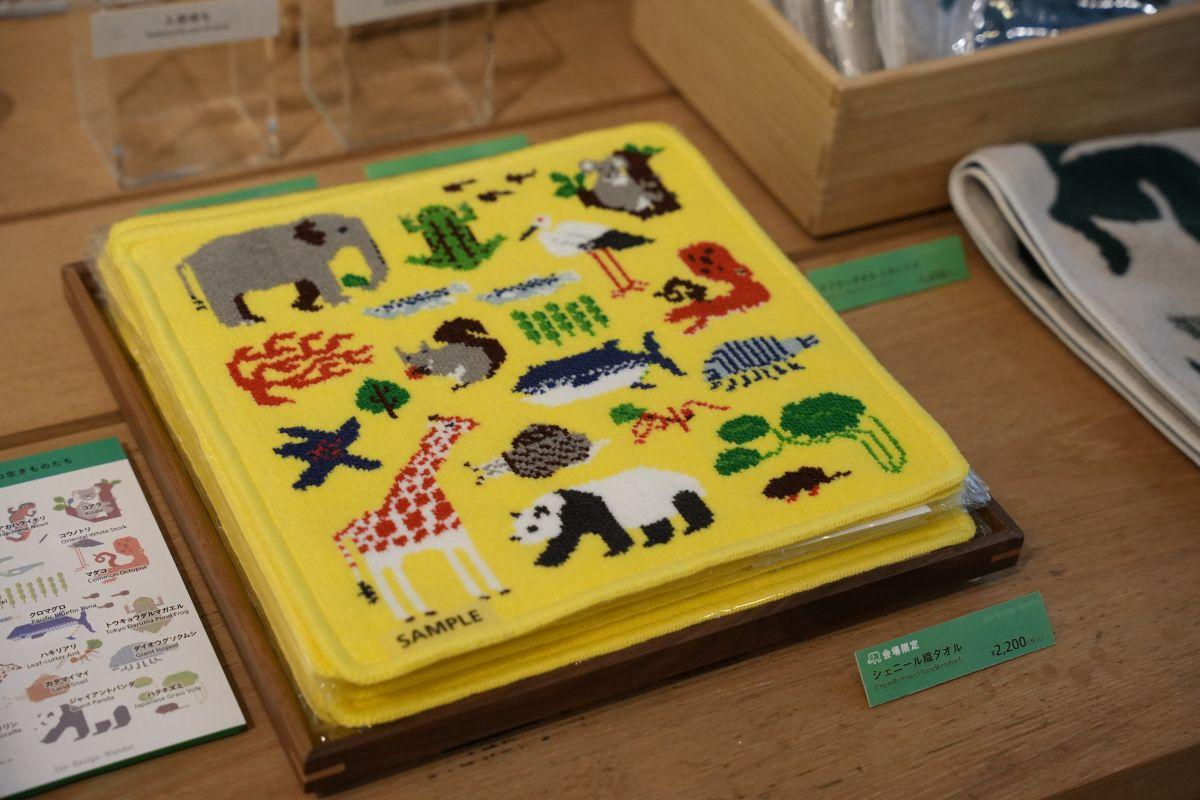 黄色地にキリン、二ホンリス、マグロ等、様々な生きものが描かれた正方形のシェニール織のタオルハンカチ、 税込2,200円