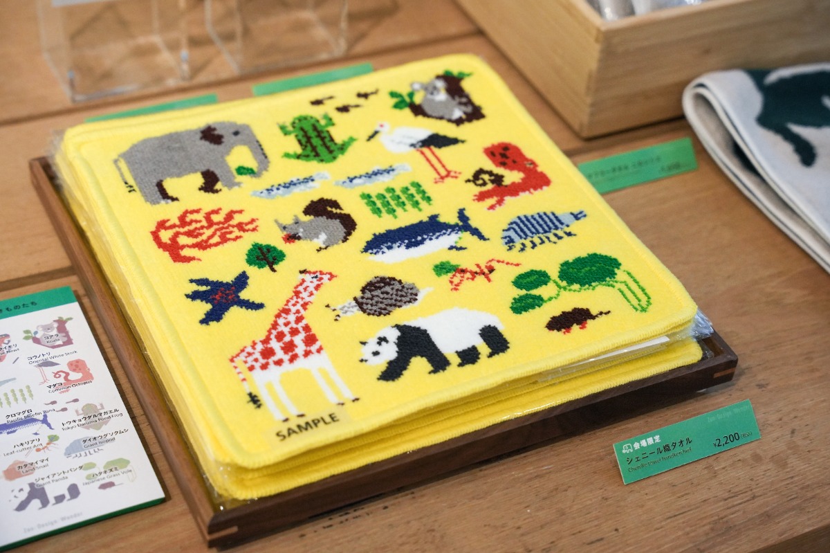 黄色地にキリン、二ホンリス、マグロ等、様々な生きものが描かれた正方形のシェニール織のタオルハンカチ、 税込2,200円